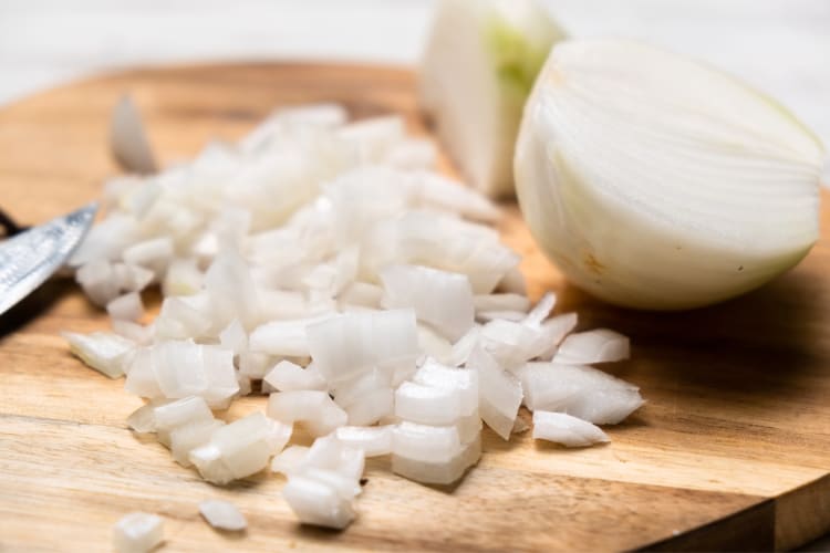 A chopped white onion next to half a white onion