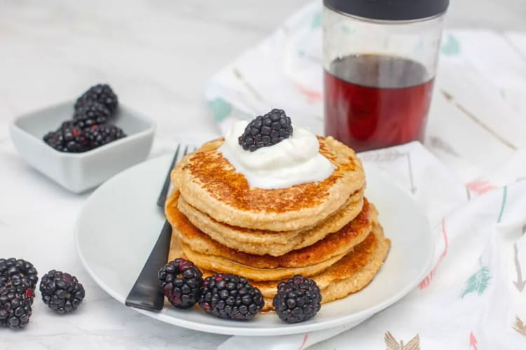 A stack of oat flour pancakes, topped with cream and mulberries, as a breakfast food idea
