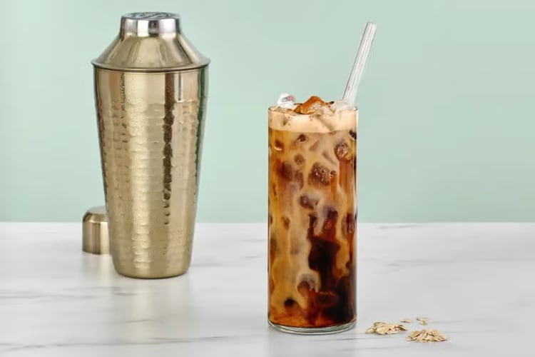 An Iced Brown Sugar Oatmilk Shaken Espresso, a sweet Starbucks drink, next to a shaker