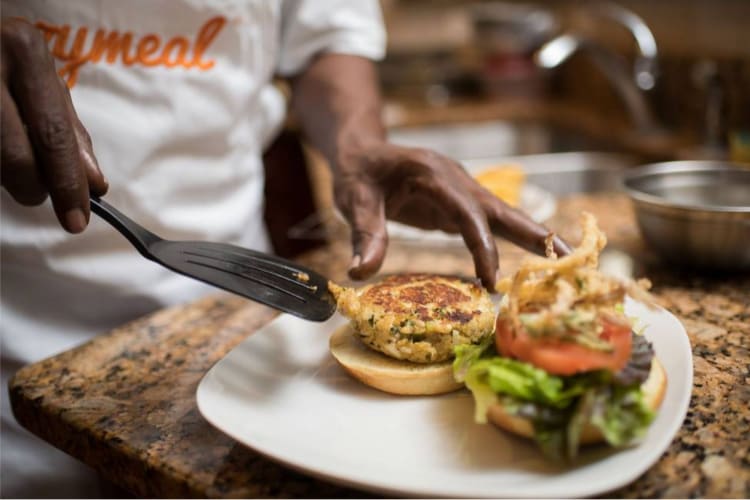 a chef plating a crab cake sandwich