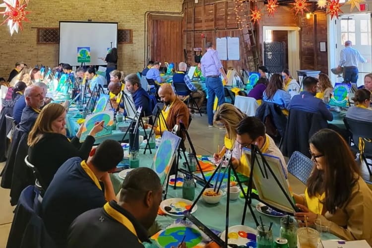 Dozens of people at a paint and sip class, which is a fun team building activity in Chicago