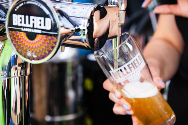 Pint of beer being poured out of a tap.