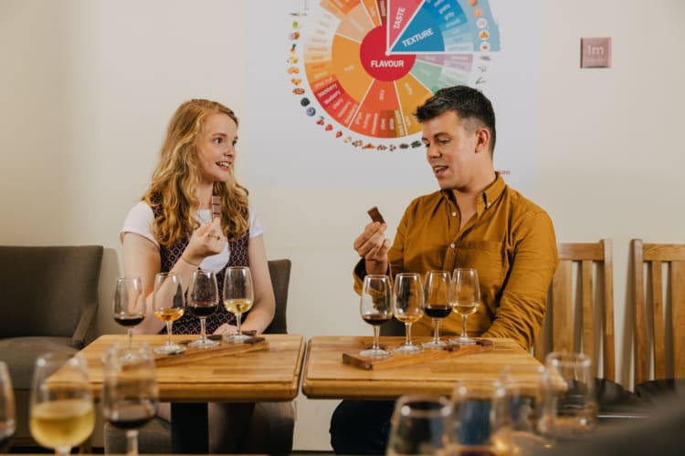 Two people tasting chocolate with a wine flight in front of them.