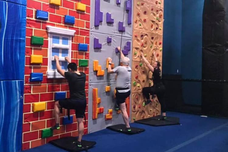 Three people ready to climb a wall at Urban Air — a great place to host a team building activity in San Antonio