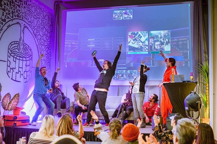 People raising their hands in the air with great elation during a gameshow