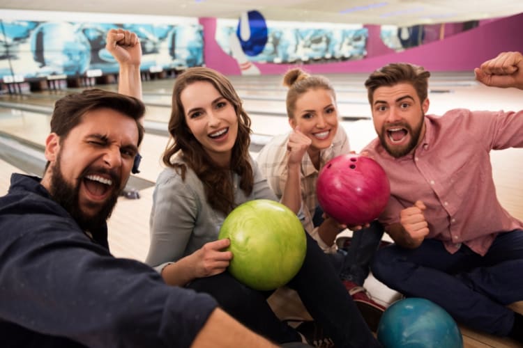 Four people strike a celebratory pose while bowling