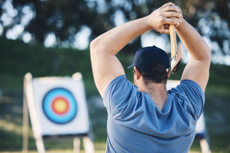 A man aims to throw an axe at a target