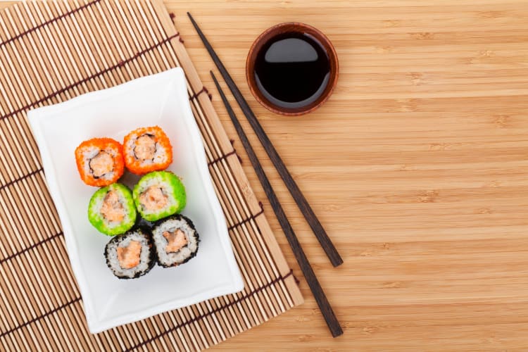 Sushi with orange, green and black tobiko on a wooden table