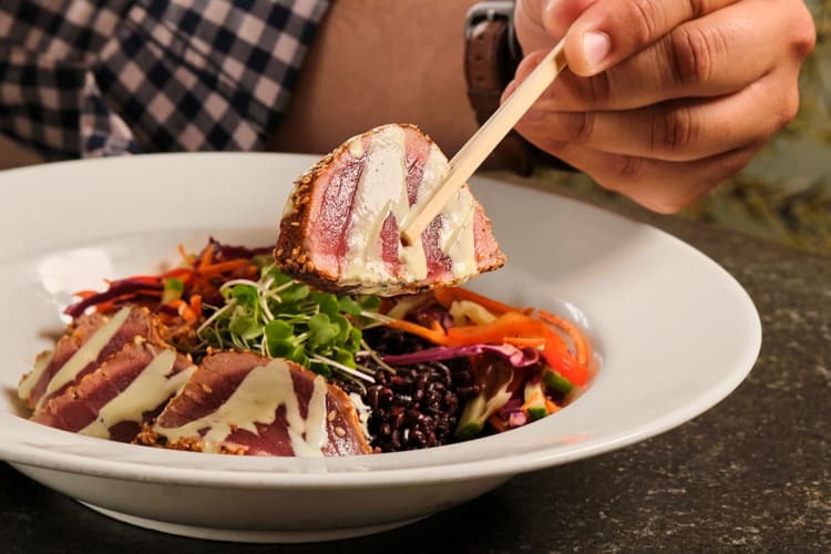 seared yellowfin tuna being eaten with chopsticks