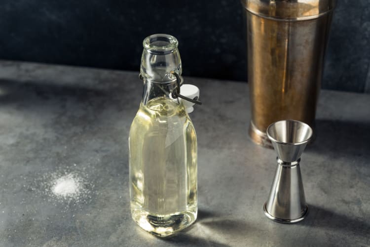 Invert sugar syrup in a glass bottle next to a jigger 