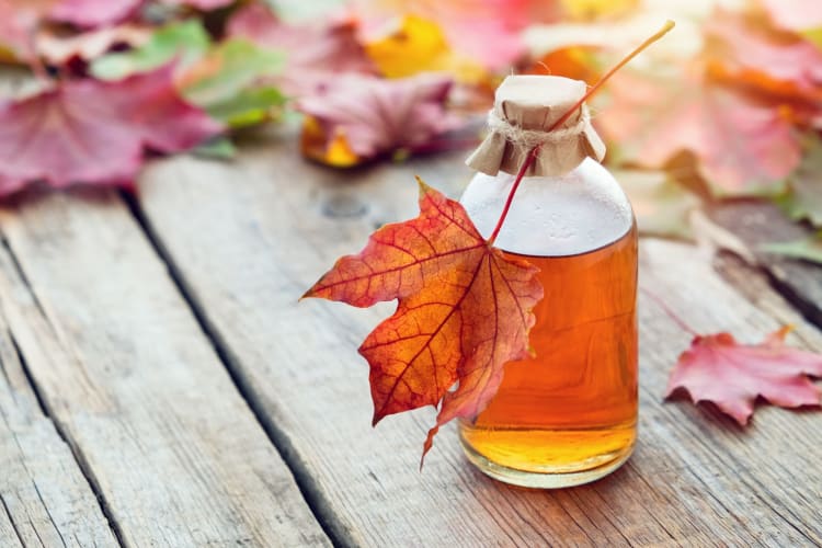 Maple syrup surrounded by maple leaves