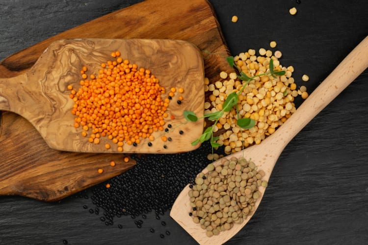 A selection of raw dry lentils on a wooden board