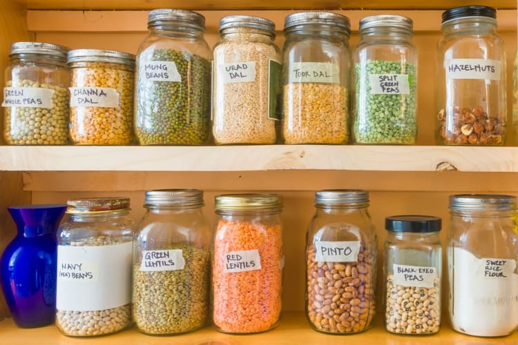 Jars of beans, peas and lentils on wooden shelves in a pantry