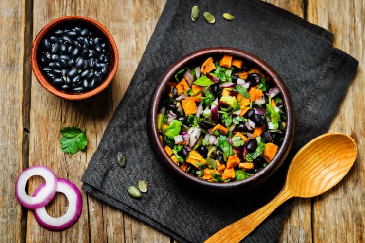 A bowl of salad with sweet potato, black beans and pepitas