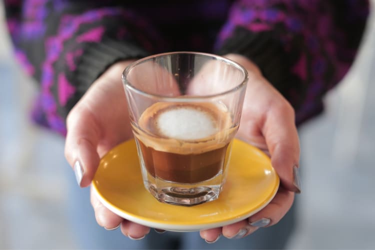 A glass cup of macchiato coffee