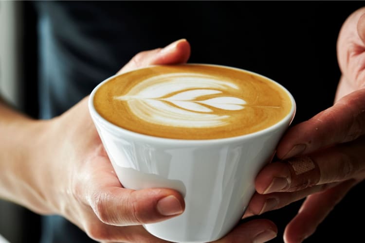 A person holds a latte coffee with latte art