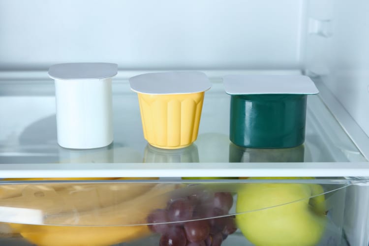 Plastic cups with yogurt in refrigerator