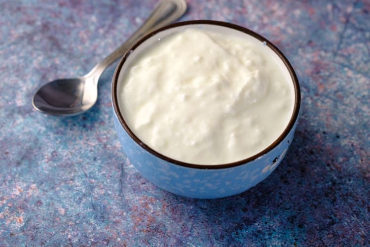 Close up of fresh yogurt in a bowl on color background