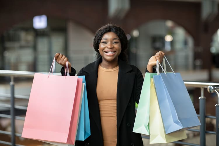 smiling woman holding up shopping bags full of Black Friday deals