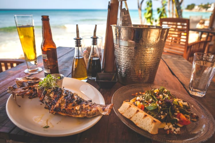 beachside table with seafood dishes and cold beer