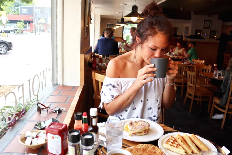 a woman sipping coffee over breakfast in a restaurant