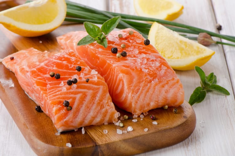 Salmon topped with salt and pepper served on a wooden board