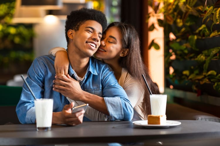 a couple snuggling in a restaurant over dessert