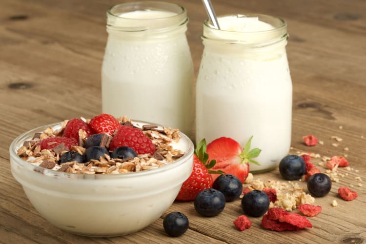 yogurt with fruit and cereal on a wooden background