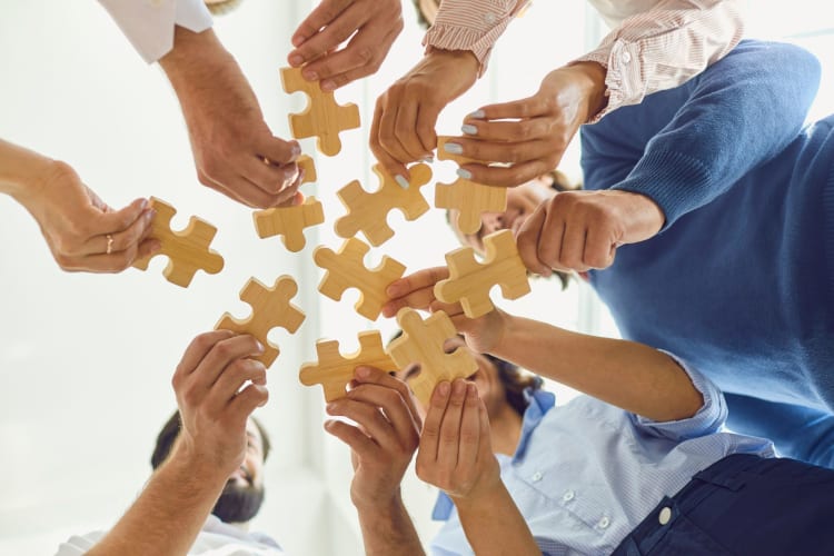 Company employees joining pieces of jigsaw puzzle during team building activity