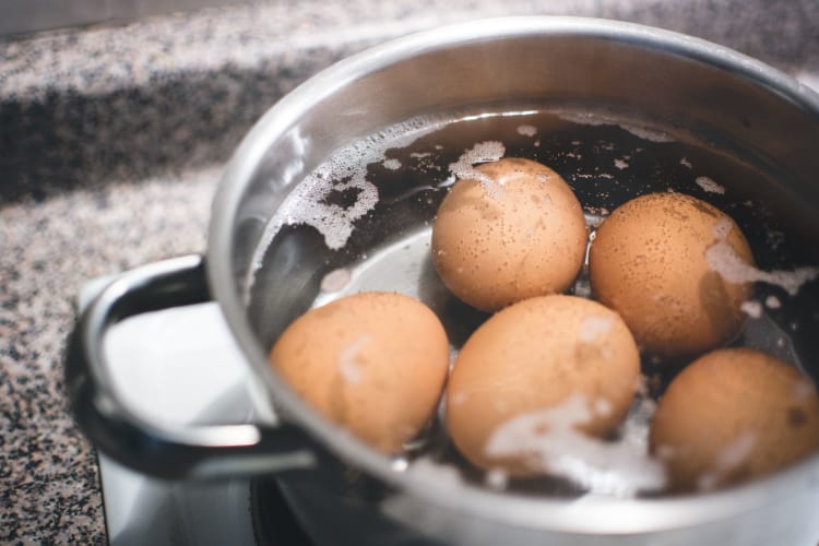 four eggs boiling in a pan