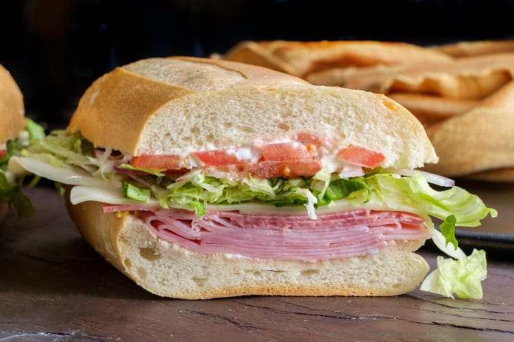 Sub sandwich served with ham, lettuces and tomatoes