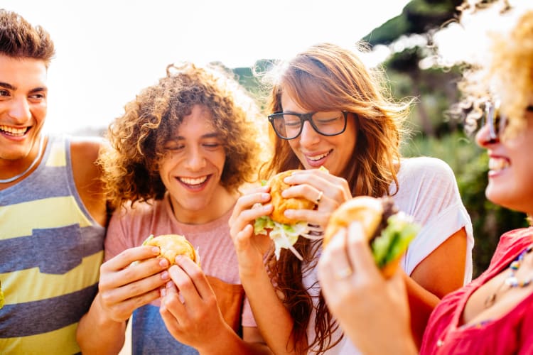 laughing friends eating pizza and having fun. They are enjoying eating and  drinking together Stock Photo