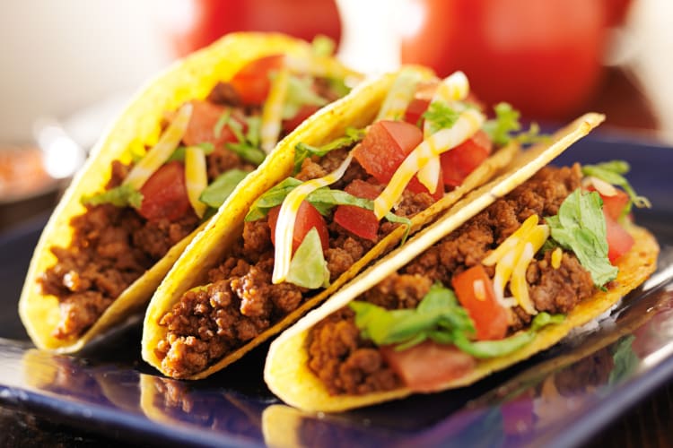 Three hard shell tacos on a blue plate