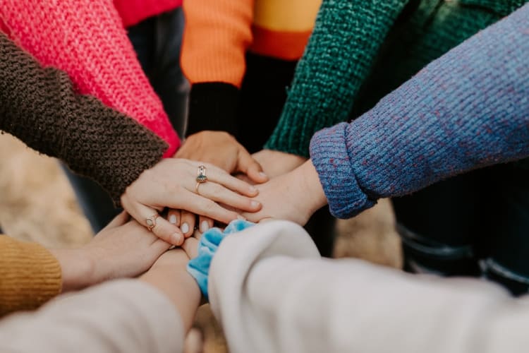 A team puts their hands in for a group huddle before starting team building activities