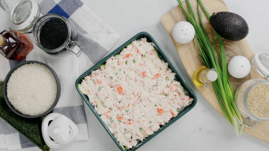 Sushi Bake Recipe: Next, layer the crab on top of the avocado and gently press down.