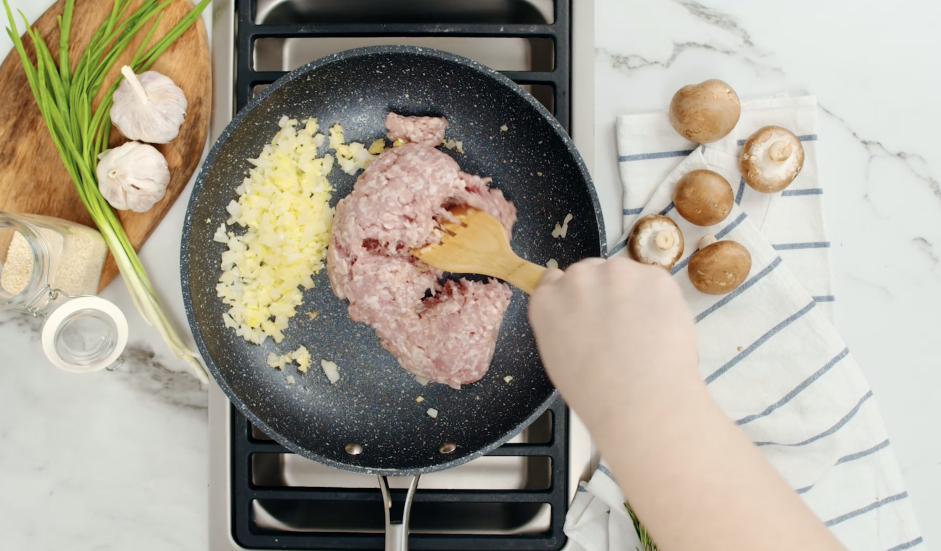 Crack Slaw (Egg Roll Bowl) Recipe: Move the onions to the sides of the pan and add in pork.