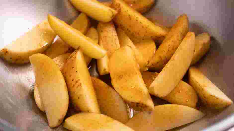 Air Fryer Potato Wedges Recipe: Transfer potatoes into a mixing bowl and toss with olive oil, Cajun seasoning and salt.