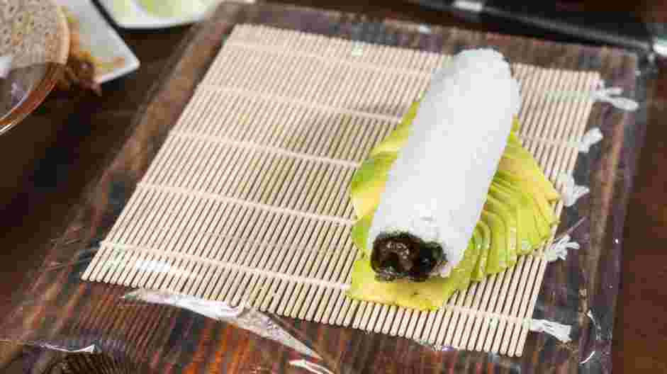 Easy Caterpillar Roll Recipe: Gently fan out the avocado slices to the length of the sushi roll and place the sushi roll on top of the avocado.