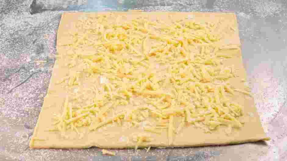 Mummy Dogs Recipe: Sprinkle half of the cheddar cheese over the puff pastry.