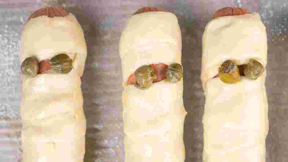 Mummy Dogs Recipe: Using a pastry brush, brush the pastry puff parts of the mummy dogs.