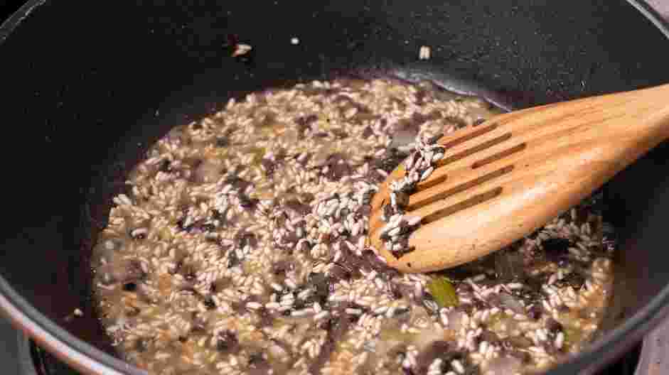 Wild Mushroom Risotto Recipe: Adjust the heat to medium-low and add one ladle of the reserved vegetable broth to the pan.