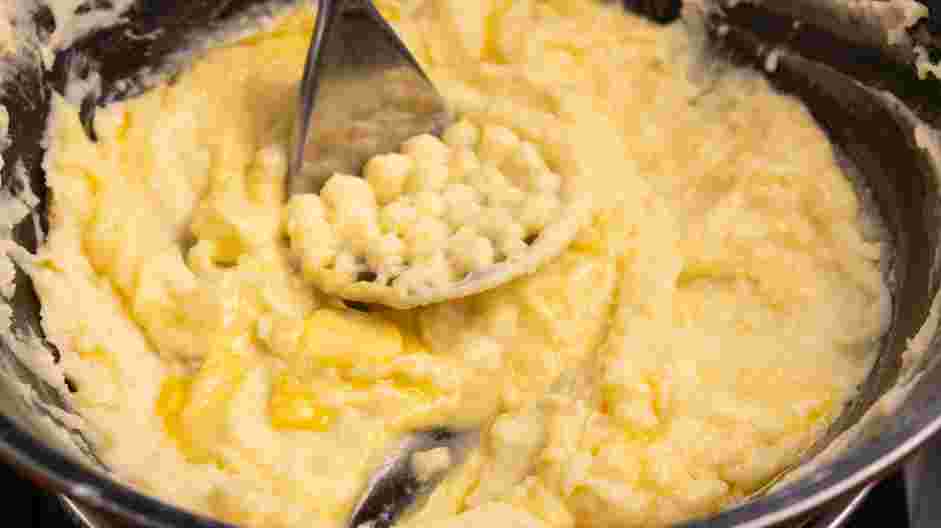 Cheesy Mashed Potatoes Recipe: Mash the potatoes to your desired texture with a potato masher.