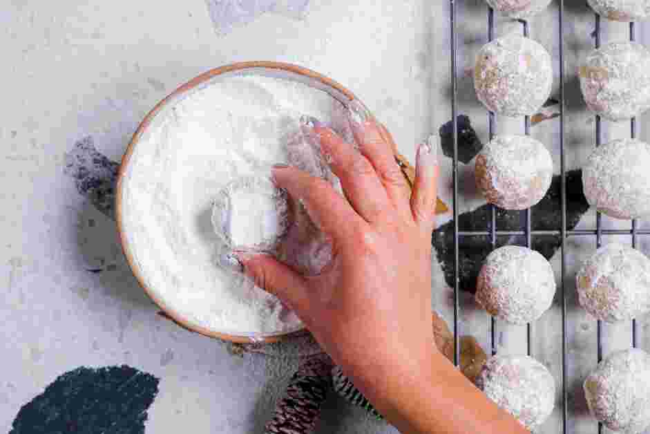 Snowball Cookies Recipe: Roll the completely cooled cookies in the reserved powdered sugar for a second time, pressing them into the powdered sugar for a thorough coating.