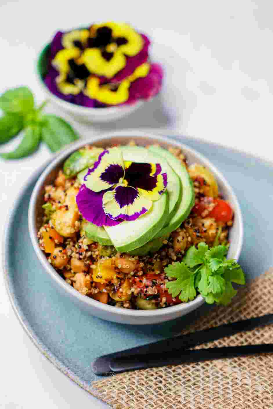 Rainbow Quinoa Bowl Recipe: Garnish with avocado slices, edible flowers and cilantro before serving.