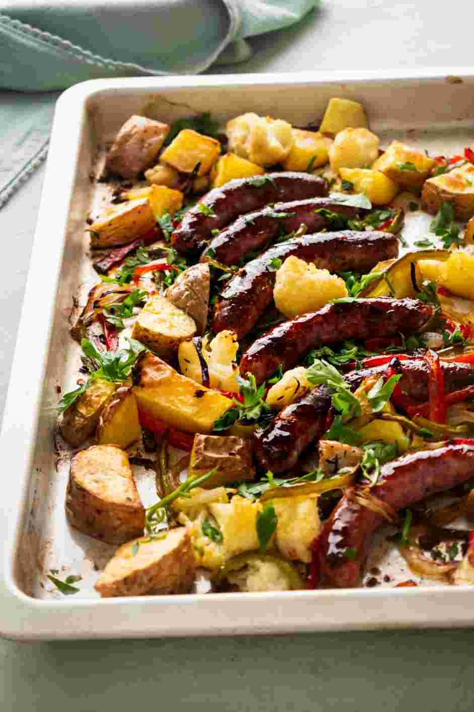 Sheet Pan Sausage and Veggies Recipe: Dress the roasted vegetables and sausage with balsamic vinegar and garnish with chopped parsley.