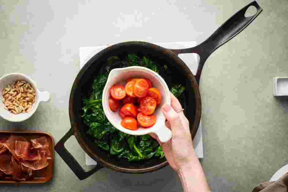 Wilted Spinach Salad Recipe: Add the halved cherry tomatoes, toasted pine nuts and torn prosciutto.