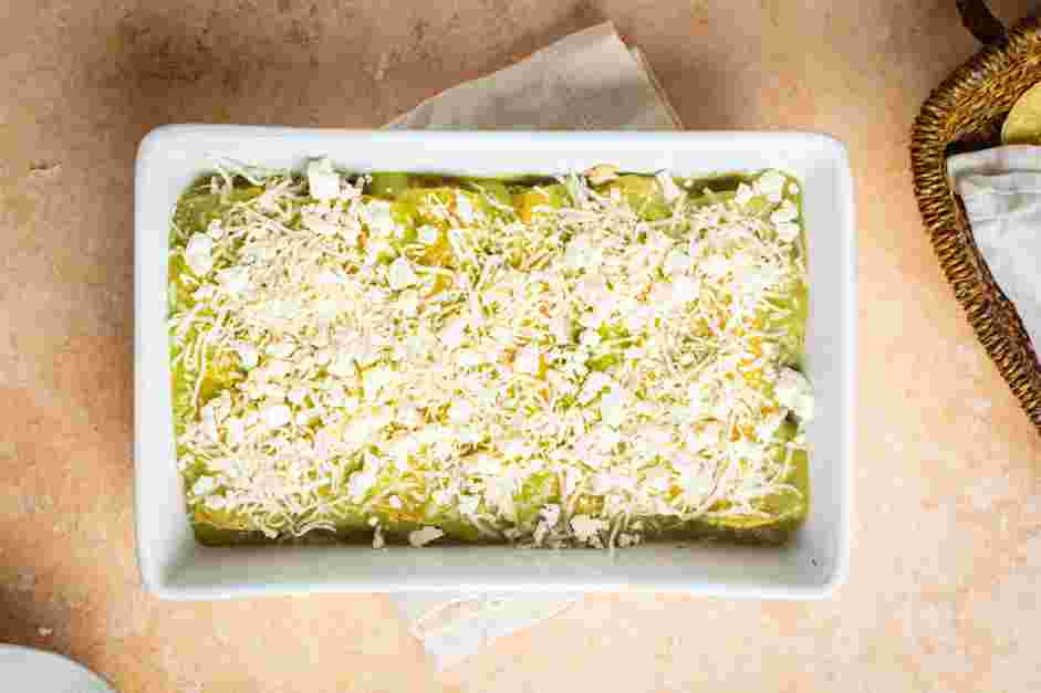 Enchiladas Verdes Recipe: Top the rolled tortillas with salsa verde and cover with shredded cheese and a sprinkling of cojita cheese.