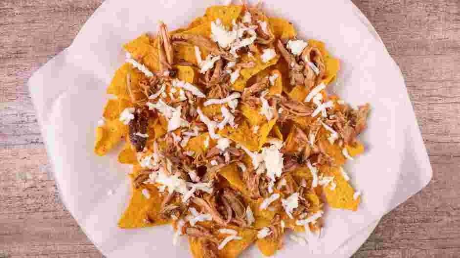 Pulled Pork Nachos Recipe: Sprinkle half of the cheddar and Monterey Jack cheese over the pulled pork.