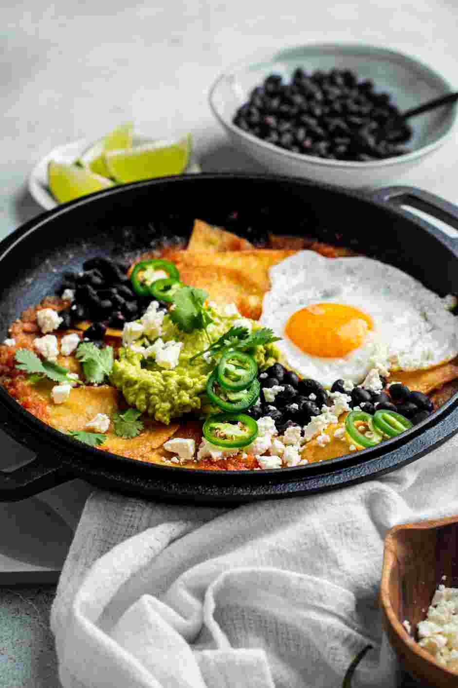 Chilaquiles Rojos Recipe: Serve on a warm serving dish with guacamole, cojita, refried beans, and fried or scrambled eggs.