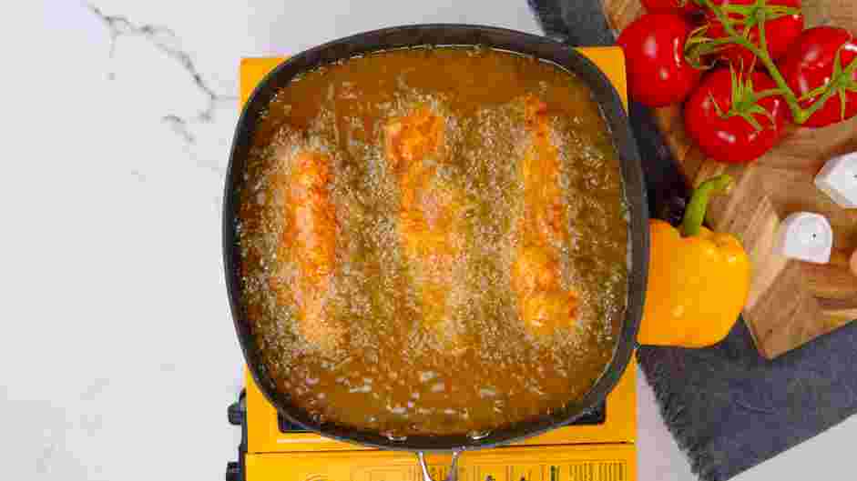 Buttermilk Chicken Tenders Recipe: Place a few breaded chicken pieces in the hot oil, keeping an eye on the temperature to ensure it does not drop below 300°F.